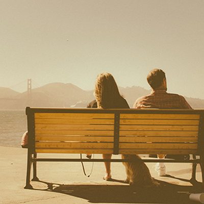 A couple sitting together on a bench, looking out over the sea